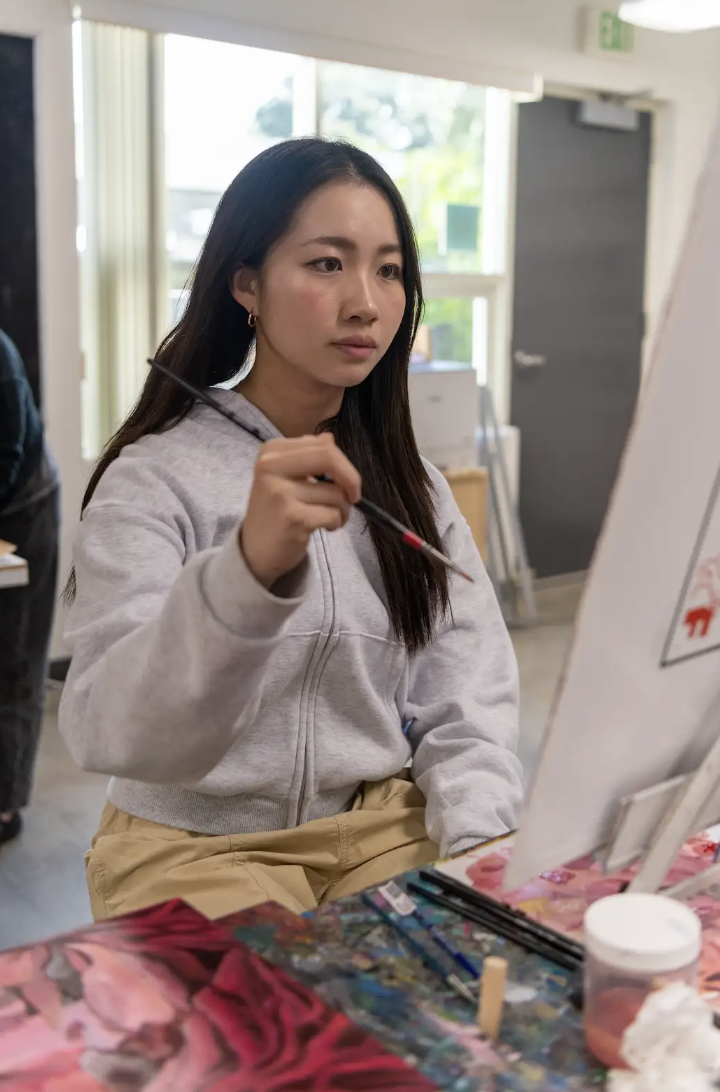 Rowena Lee paints her art piece for the art show.